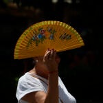 Una mujer se tapa con un abanico mientras camina por el centro histórico de Córdoba 