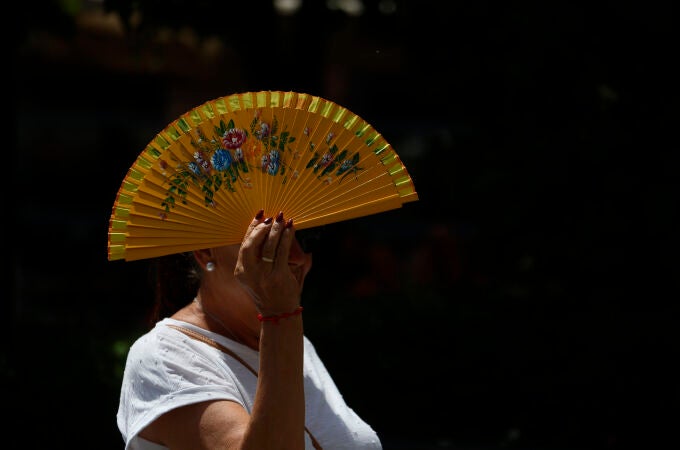 Imagen de una mujer cubriéndose del calor con un abanico.