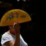 Imagen de una mujer cubriéndose del calor con un abanico.