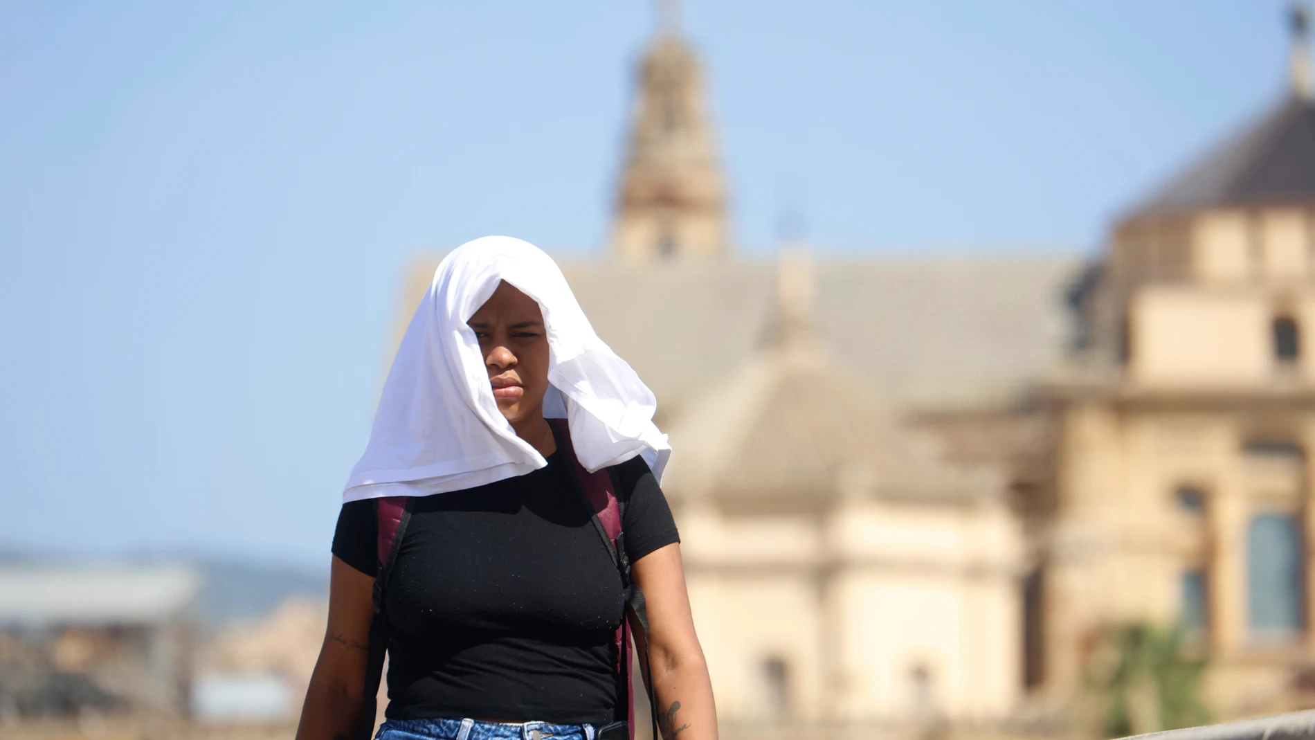 GRAFAND9965. CÓRDOBA, 09/07/2025.-Una mujer se tapa con una camiseta mientras camina por el Puente Romano, este miércoles cuando se mantiene el aviso amarillo en Córdoba, donde se alcanzarán los 40 grados. Según los datos de la Agencia Estatal de Meteorología (Aemet) sitúan al valle del Guadalquivir, entre las provincias de Jaén y Córdoba, como la zona más calurosa del país puesto que no hay precedentes de que una comarca haya recibido durante 31 días consecutivos (en concreto desde el pasado...