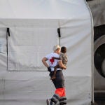 Una persona de la Cruz Roja con un menor, en el Puerto de la Restinga