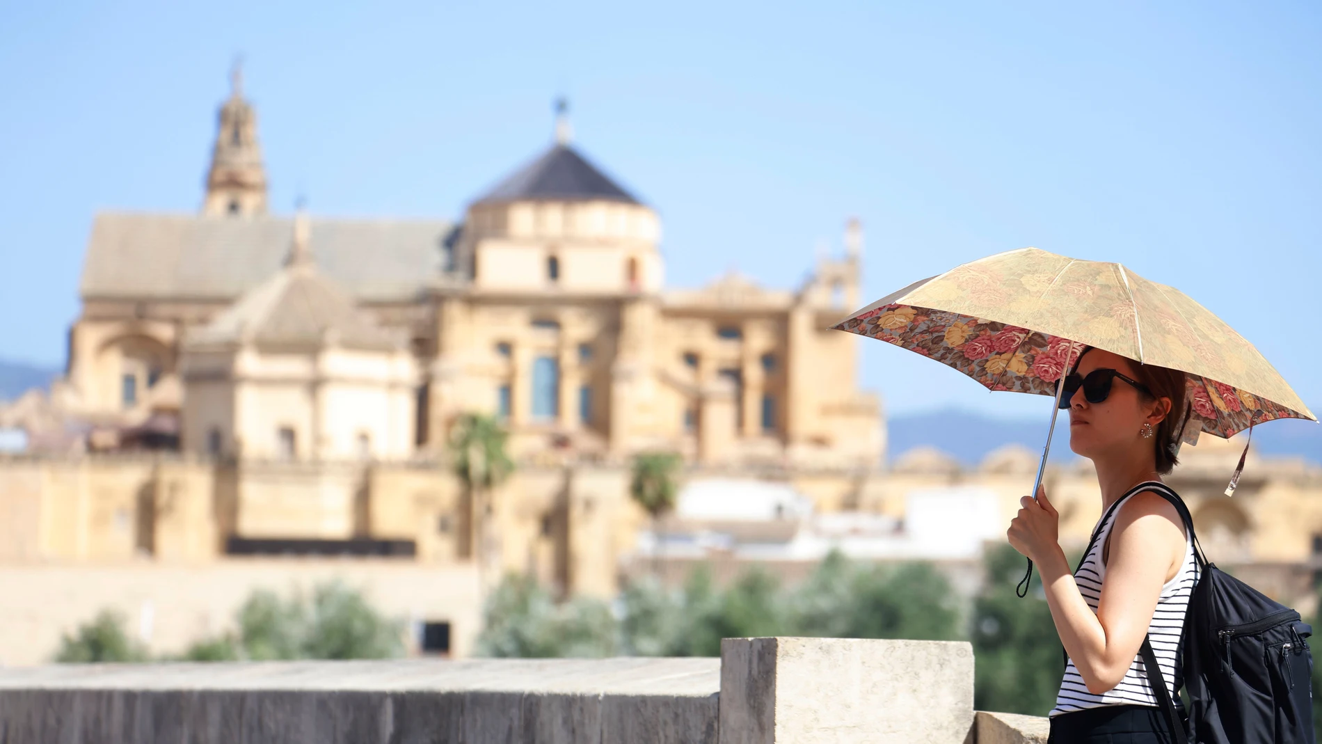 GRAFAND9968. CÓRDOBA, 09/07/2025.-Una mujer se tapa con una sombrilla mientras camina por el Puente Romano, este miércoles cuando se mantiene el aviso amarillo en Córdoba, donde se alcanzarán los 40 grados. Según los datos de la Agencia Estatal de Meteorología (Aemet) sitúan al valle del Guadalquivir, entre las provincias de Jaén y Córdoba, como la zona más calurosa del país puesto que no hay precedentes de que una comarca haya recibido durante 31 días consecutivos (en concreto desde el pasad...