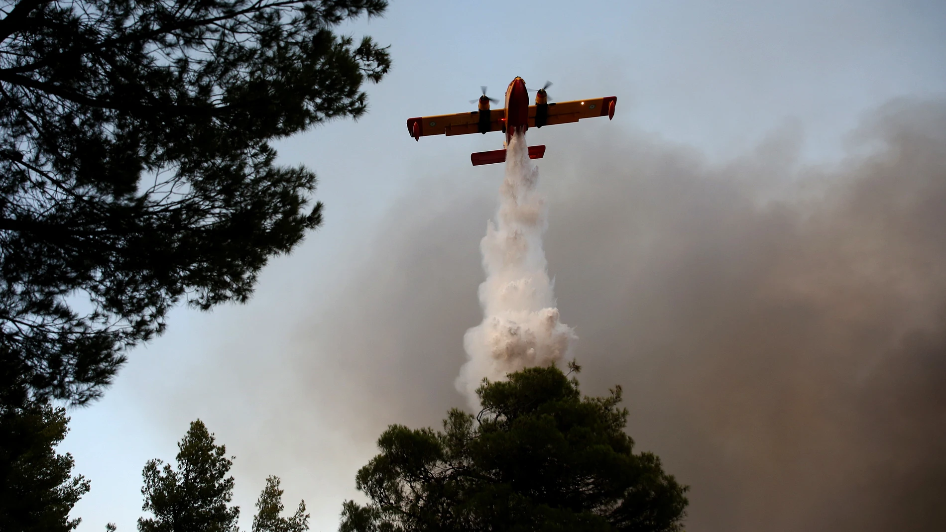 OROPOS (Greece), 09/07/2025.- A firefighting airplane battles a wildfire that broke out near the village of Asprochori in the region of Oropos, East Attica, Greece, 09 July 2025, leading to the evacuation of residents. A total of 140 firefighters with 5 rough terrain teams, 39 fire trucks, and many volunteers are fighting the fire. Until sunset, 13 airplanes and 8 helicopters were also at the site. (incendio forestal, Grecia) EFE/EPA/ORESTIS PANAGIOTOU