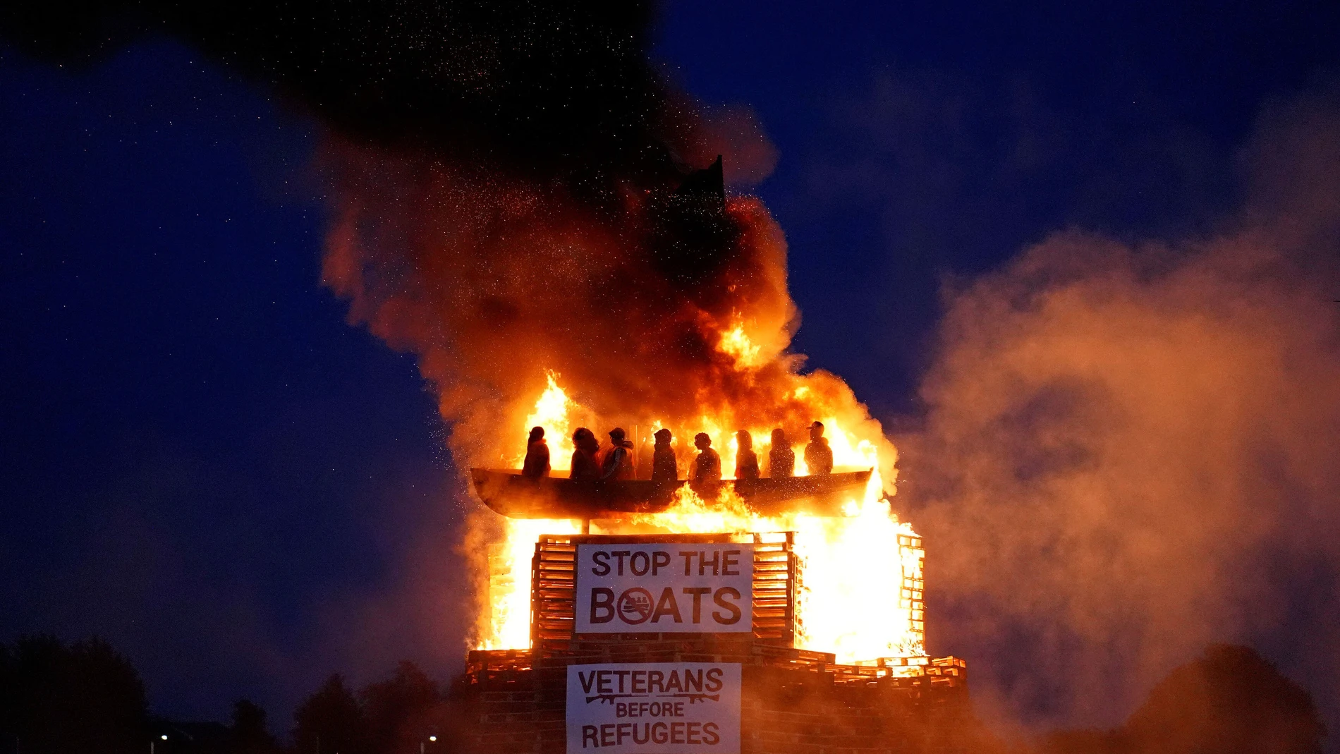 Effigies of migrants in a boat burn atop a bonfire at Moygashel, County Tyrone, Northern Ireland, ahead of events to mark the Twelfth of July, Thursday July 10, 2025. (Niall Carson/PA via AP)