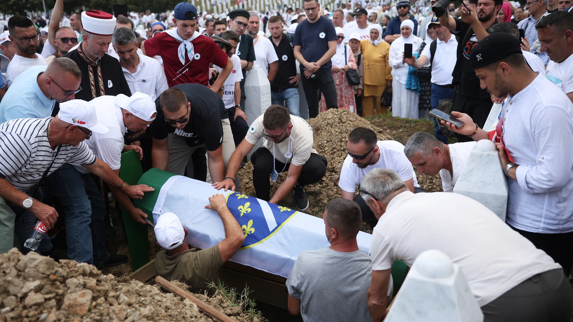 People lower into a grave the coffin of a victim of the Srebrenica genocide at the Memorial Center in Potocari, Bosnia, Friday, July 11, 2025. (AP Photo/Armin Durgut)