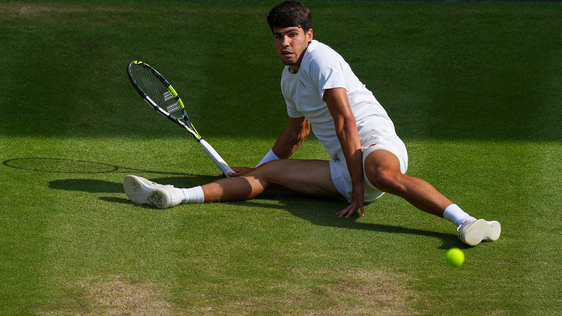 Carlos Alcaraz of Spain slips as he returns a shot by Italy's Jannik Sinner in the men's singles final at the Wimbledon Tennis Championships in London, Sunday, July 13, 2025. (AP Photo/Joanna Chan)