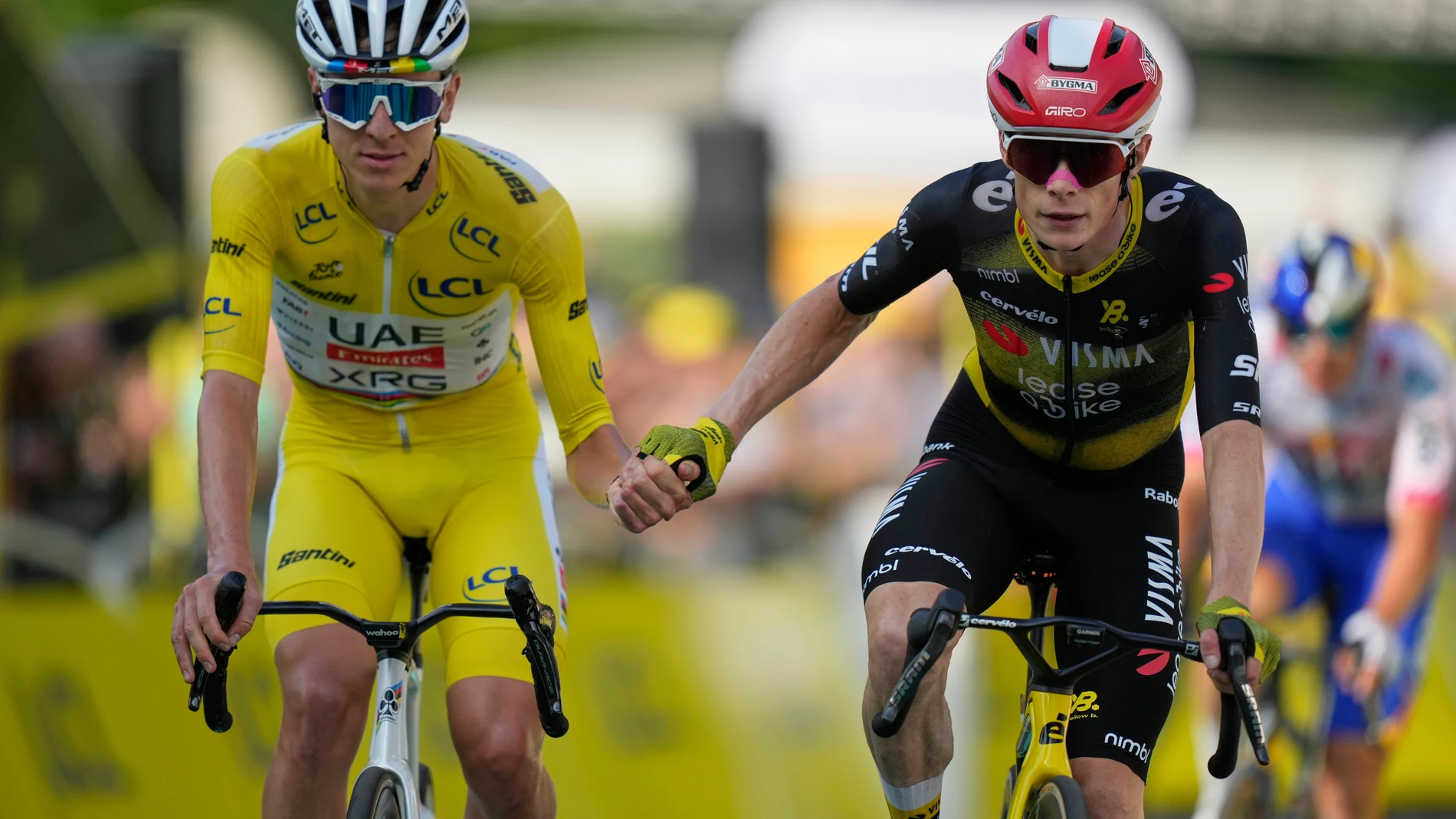 Slovenia's Tadej Pogacar, wearing the overall leader's yellow jersey, and Denmark's Jonas Vingegaard, cross the finish line hand-in-hand of the the tenth stage of the Tour de France cycling race over 165.3 kilometers (102.7 miles) with start in Ennezat and finish in Le Mont-Dore Puy de Sancy, France, Monday, July 14, 2025. (AP Photo/Mosa'ab Elshamy)