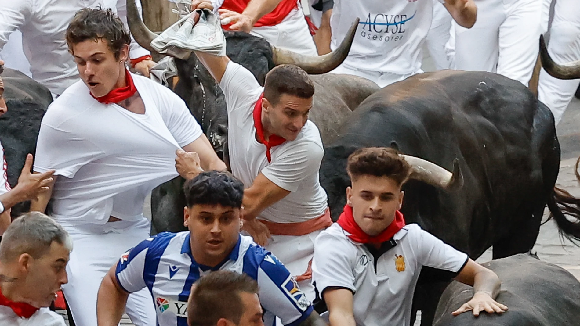 PAMPLONA, 14/07/2025.- Varios mozos perseguidos de cerca por toros de la ganadería sevillana de Miura durante el octavo y último encierro de los Sanfermines este lunes. EFE/Villar López