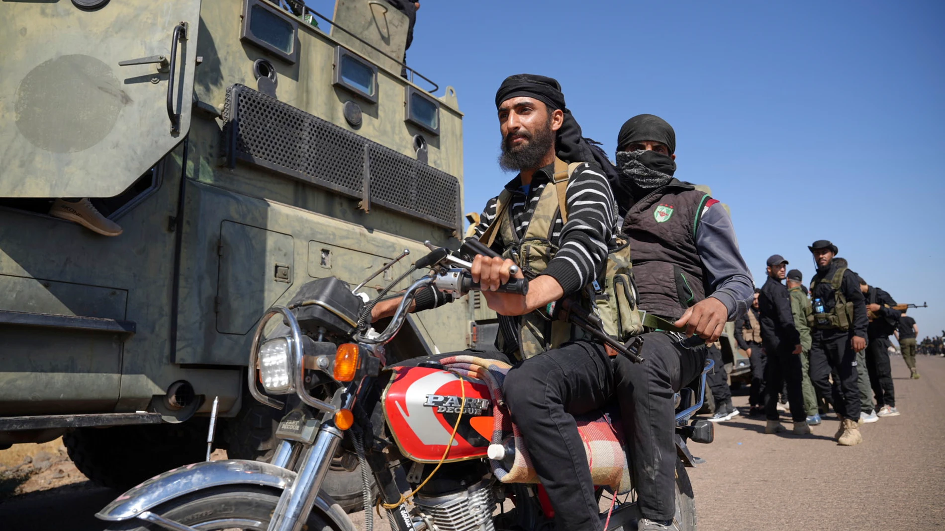 Dos combatientes de clanes beduinos suníes conducen su motocicleta al paso de las fuerzas de seguridad gubernamentales sirias desplegadas en las afueras de la provincia de Sweida, donde estallaron enfrentamientos entre milicias drusas y clanes beduinos suníes, en el sur de Siria