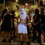 Residents wearing head coverings and face masks congregate in the street following three days of unrest in Torre Pacheco, in eastern Spain on July 14, 2025. Spanish police have arrested ten people over rare anti-migrant unrest that rocked the town of Torre Pacheco, authorities said on Monday. Three nights of violence erupted on Friday after a 68-year-old man told local media three youths of North African origin had beaten him up in the street of the southeastern town.