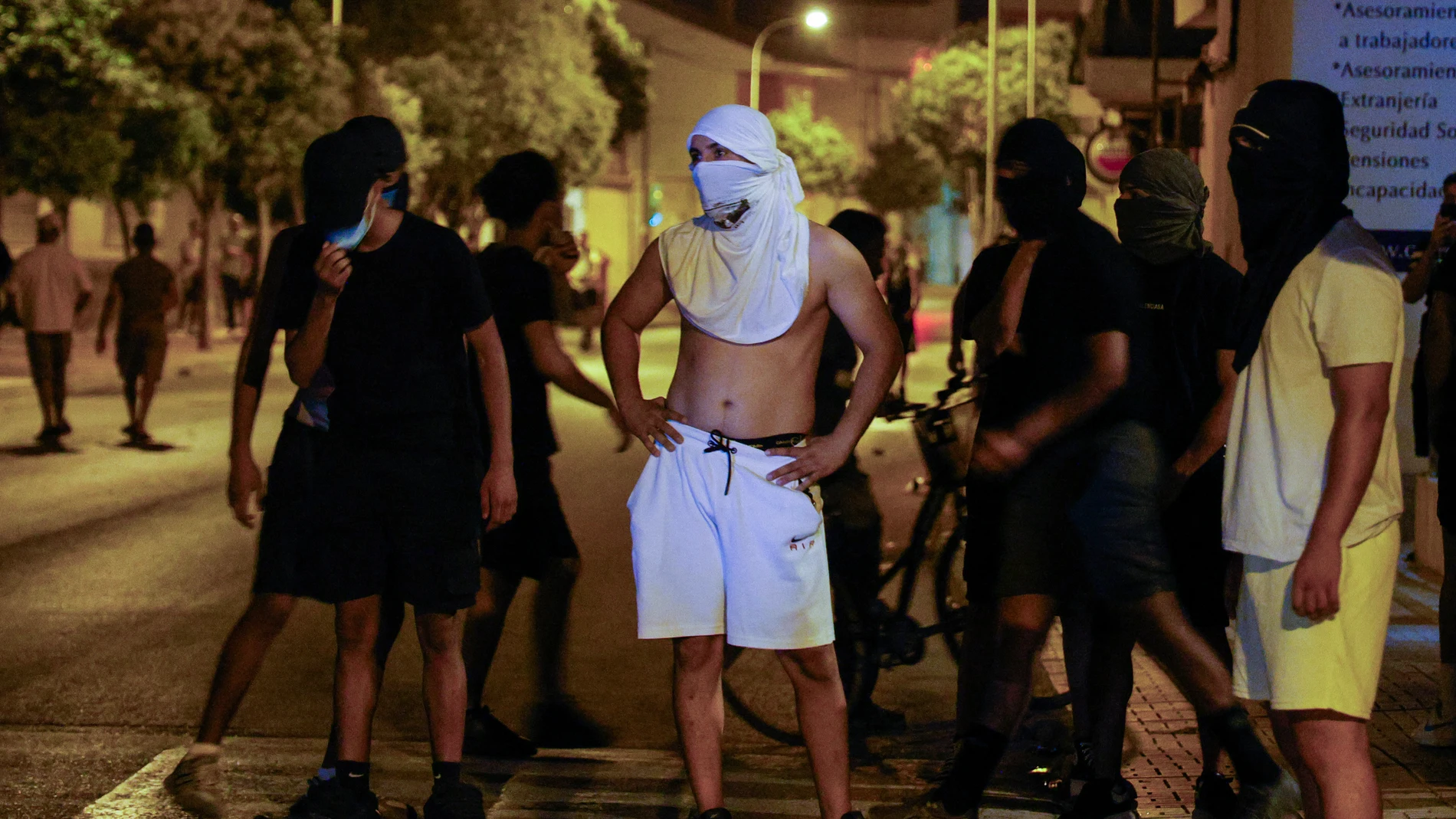Residents wearing head coverings and face masks congregate in the street following three days of unrest in Torre Pacheco, in eastern Spain on July 14, 2025. Spanish police have arrested ten people over rare anti-migrant unrest that rocked the town of Torre Pacheco, authorities said on Monday. Three nights of violence erupted on Friday after a 68-year-old man told local media three youths of North African origin had beaten him up in the street of the southeastern town.