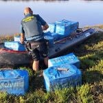 Un agente de la Guardia Civil con algunos de los fardos interceptados