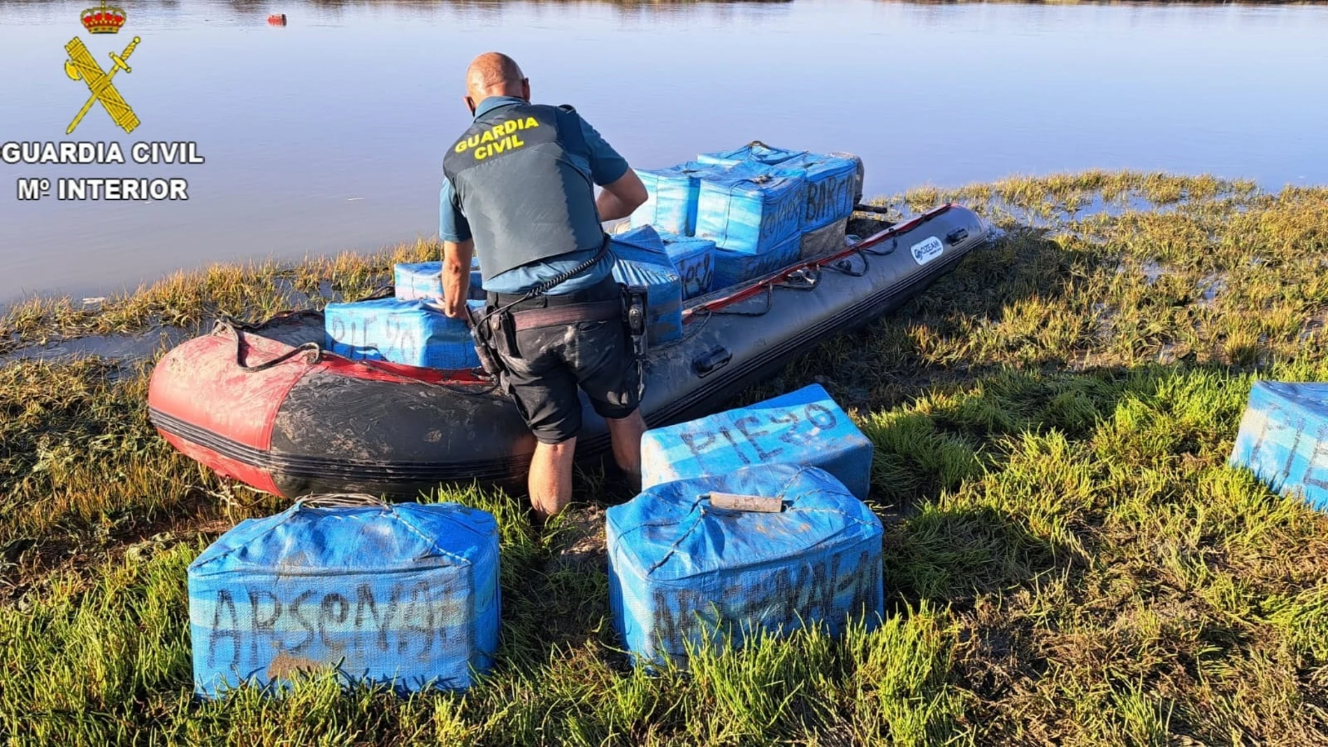 Un agente de la Guardia Civil con algunos de los fardos interceptados
