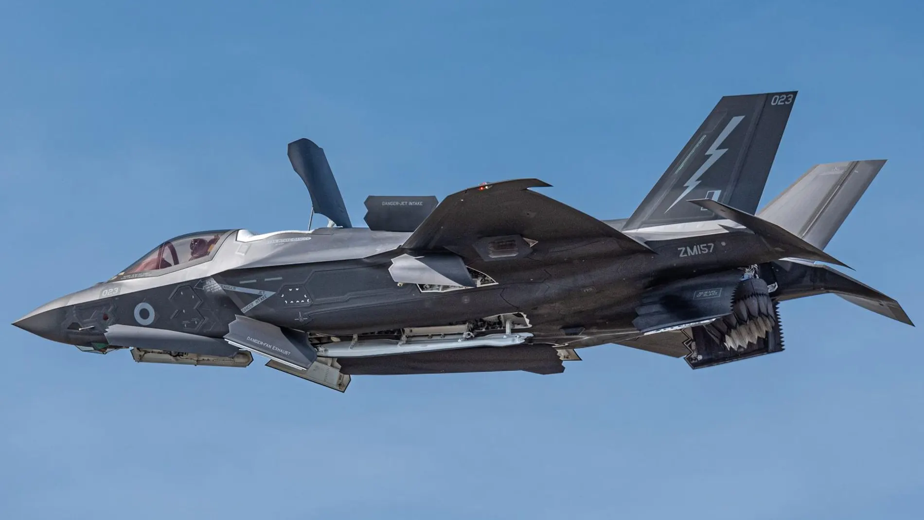 Aparece un avión de combate volando en el cielo durante unas maniobras abriendo sus compartimentos de armas