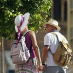 Dos personas con ropa veraniega y sombreros en Málaga