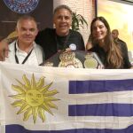 Alfredo Evangelista posa con una bandera uruguaya entre Gilberto Mendoza, presidente de la WBA, y de la boxeadora uruguaya Cecilia Comunales