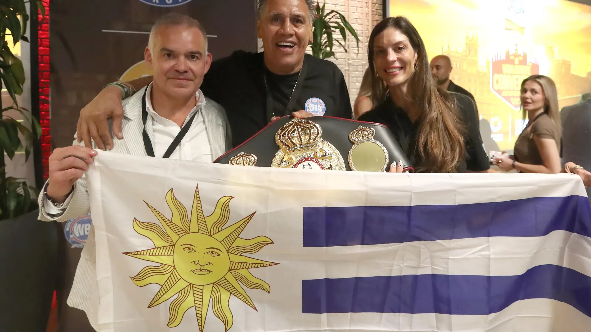 Alfredo Evangelista posa con una bandera uruguaya entre Gilberto Mendoza, presidente de la WBA, y de la boxeadora uruguaya Cecilia Comunales