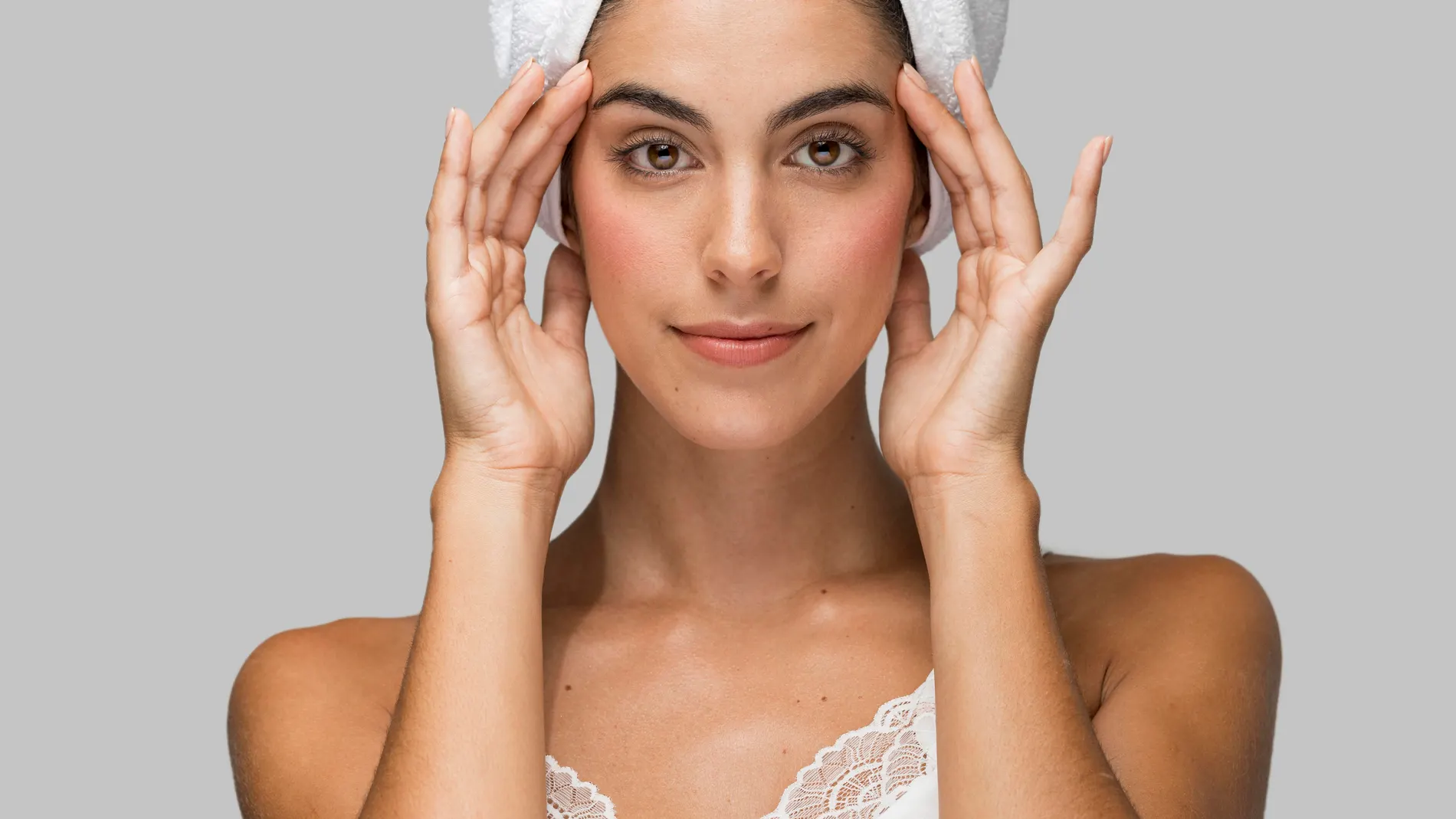 Mujer con la piel limpia y toalla en la cabeza durante su rutina facial.