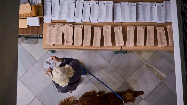 Una mujer coge una papeleta para votar en las elecciones generales