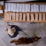 Una mujer coge una papeleta para votar en las elecciones generales