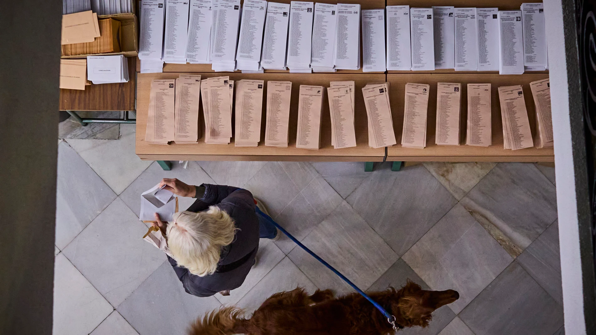 Una mujer coge una papeleta para votar en las elecciones generales