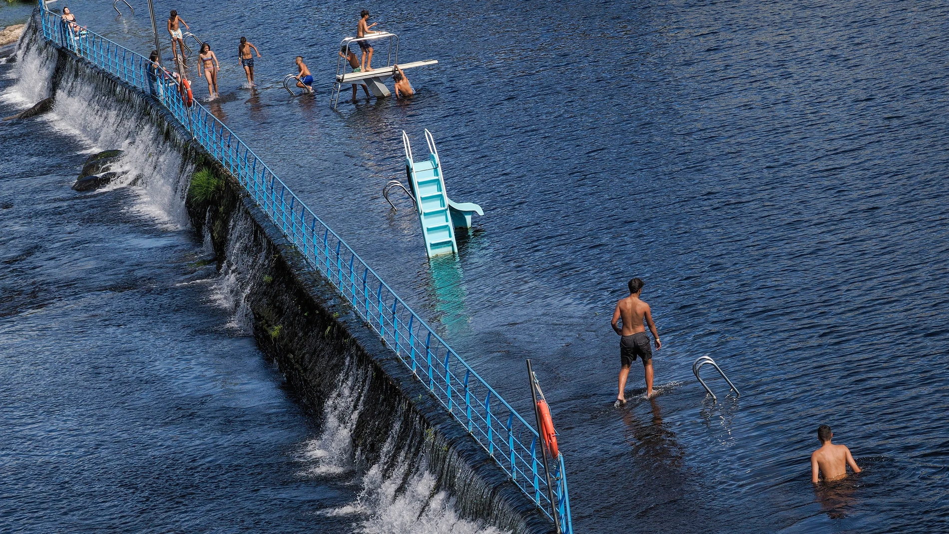 LUGO, 22/07/2025.- Varias personas dentro del río Miño, este martes en Lugo. A partir de este miércoles Galicia irá recuperando lentamente la influencia de las altas presiones con circulación del viento del norte, según el pronóstico. EFE/ Eliseo Trigo