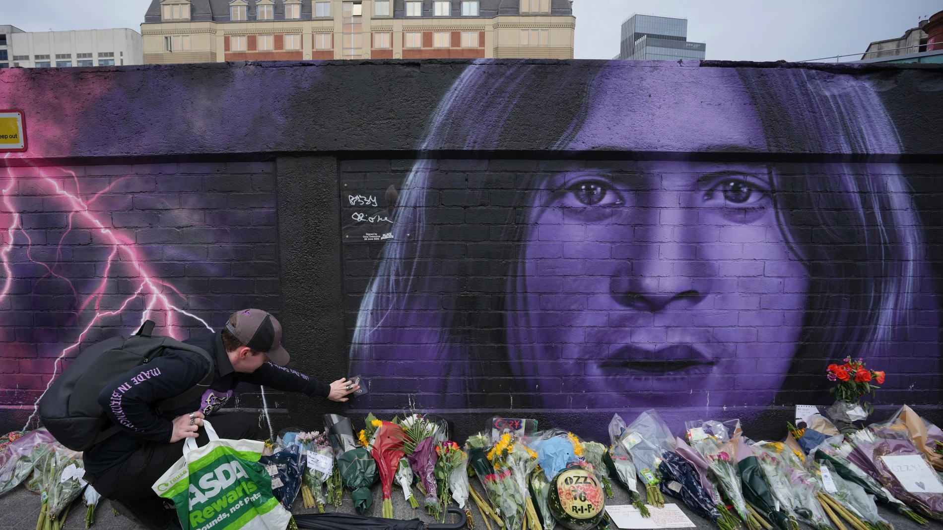 A fan lay flowers to commemorate the death of Ozzy Osbourne in Birmingham, Wednesday, July 23, 2025. (AP Photo/Kin Cheung)
