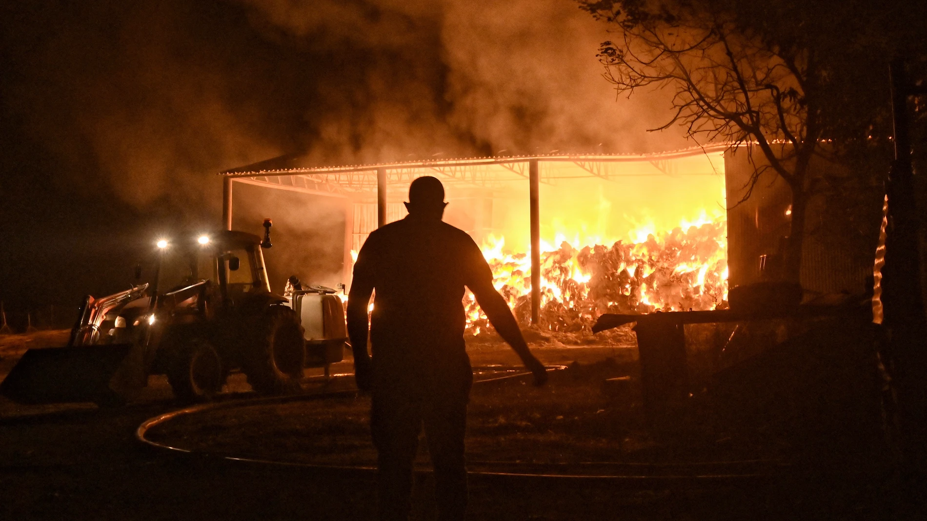 FOTODELDÍA Feneos (Grecia), 23/07/2025. Bomberos y voluntarios combaten un almacén en llamas durante un incendio forestal en la aldea de Feneos, municipio de Corinto, Grecia, este miércoles. Según el Cuerpo de Bomberos, los equipos de extinción lograron controlar el incendio que se desató en una zona boscosa de la zona montañosa de Feneos. EFE/ EPA/ANA-MPA/Vassilis Psomas