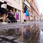 Personas reflejadas en un charco en Sevilla