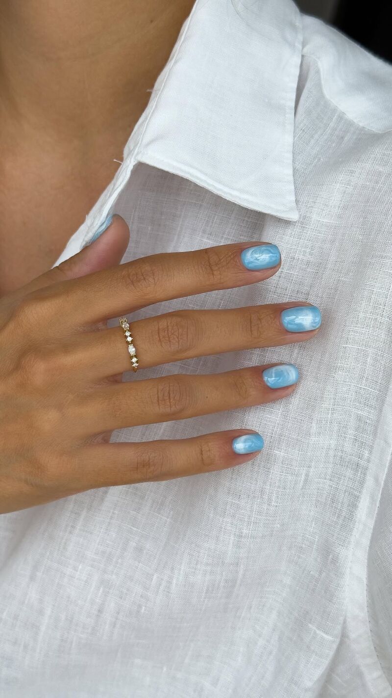 Mármol azul cielo en uñas cortas.