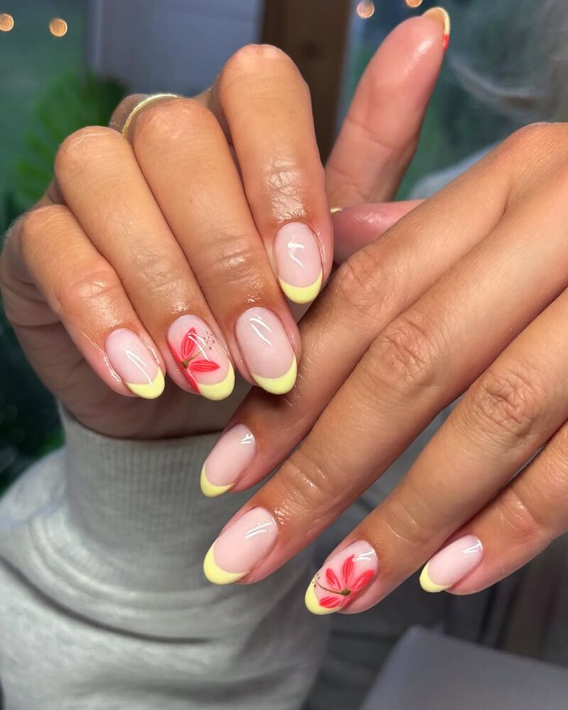 Manicura francesa amarilla con flores tipo hibisco.