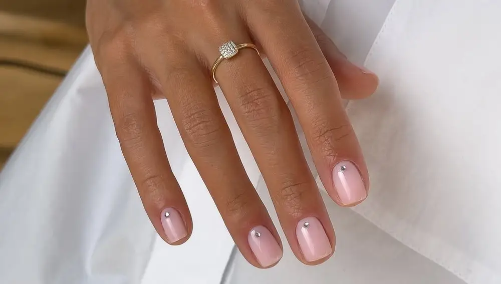 Uñas cortas con base nude y una perlita central en cada una.
