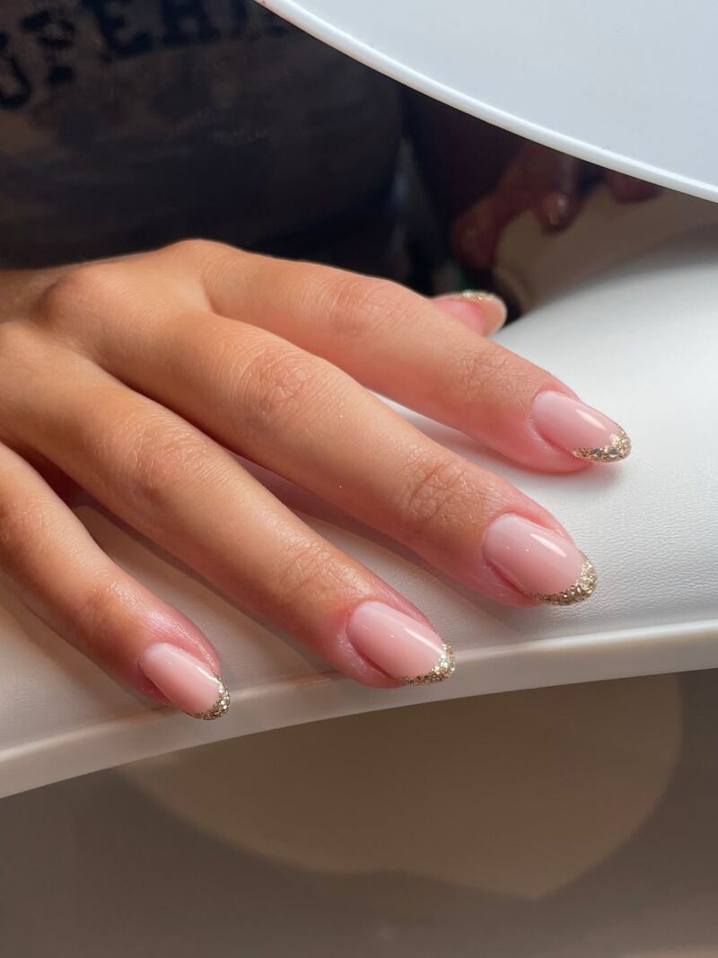 Manicura francesa con punta glitter dorado.