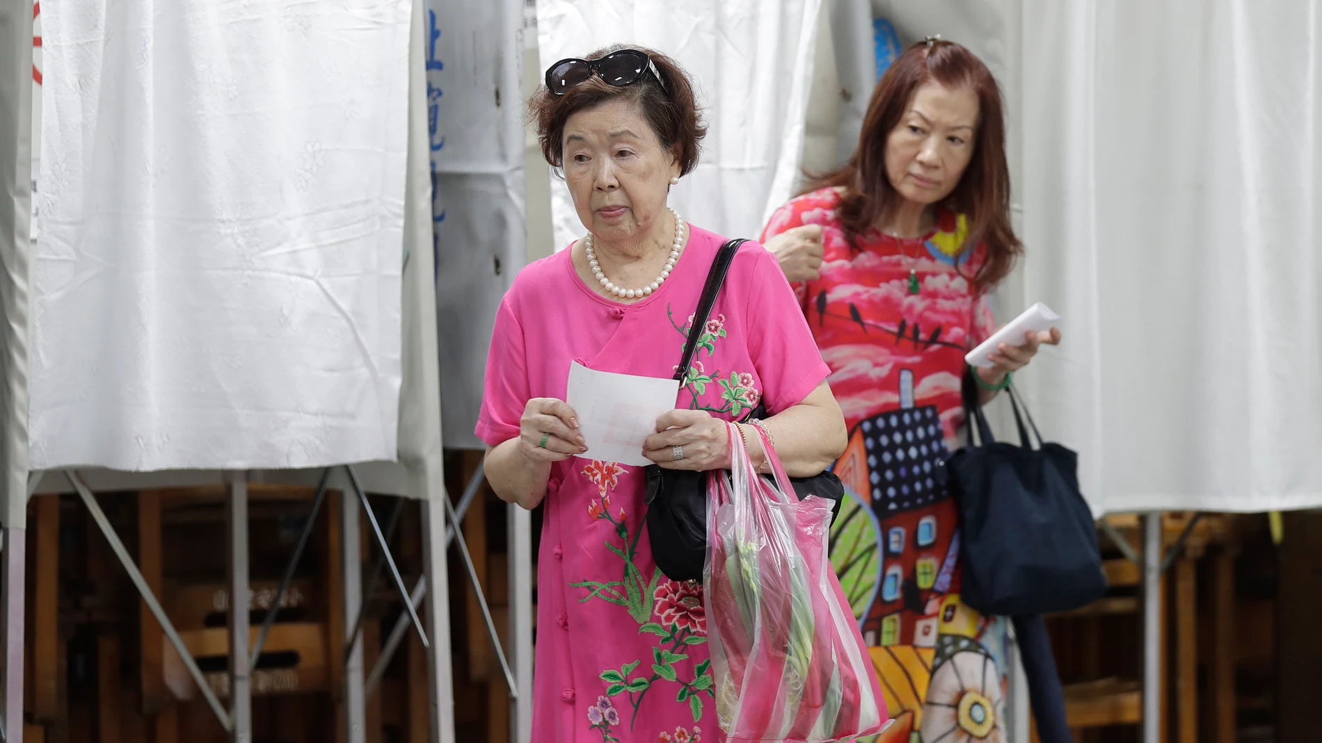 Voters emerge from voting booths at a polling station in Taipei, Taiwan, Saturday, July 26, 2025 as Taiwanese are casting their votes to determine whether to oust about one-fifth of their lawmakers, all from the opposition Nationalist Party, in elections. (AP Photo/Chiang Ying-ying)