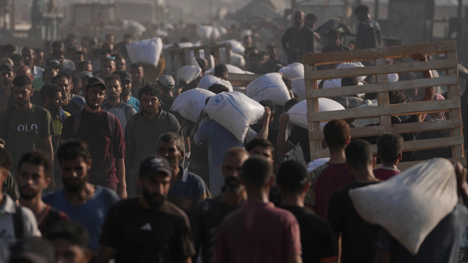 Palestinians carry sacks of flour unloaded from a humanitarian aid convoy that reached Gaza City from the northern Gaza Strip, Saturday, July 26, 2025. (AP Photo/Jehad Alshrafi)