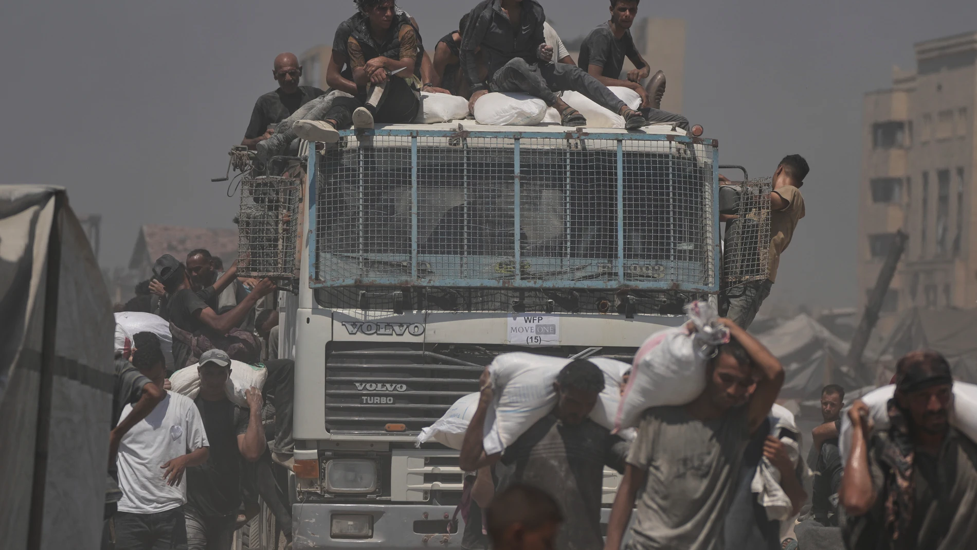 Palestinians carry sacks of flour unloaded from a humanitarian aid convoy that reached Gaza City from the northern Gaza Strip, Sunday, July 27, 2025. (AP Photo/Jehad Alshrafi)