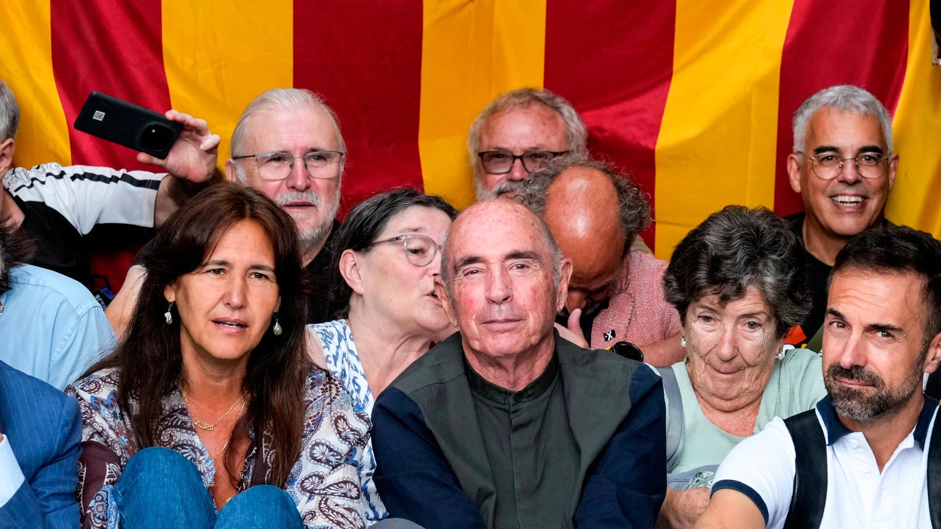 GRAFCAT880. BARCELONA, 28/07/2025.- El presidente de la ANC, Lluis Llach (c), y la expresidenta del Parlament, Laura Borràs (i), junto a varias decenas de personas convocadas por la ANC en protesta por el traslado de las pinturas de Sijena, bloquean la entrada de oficinas del Museo Nacional de Arte de Cataluña (MNAC), donde este lunes se espera la visita de técnicos del gobierno de Aragón para hacer un estudio de las pinturas de Sijena y examinan la documentación sobre su tratamiento y conser...
