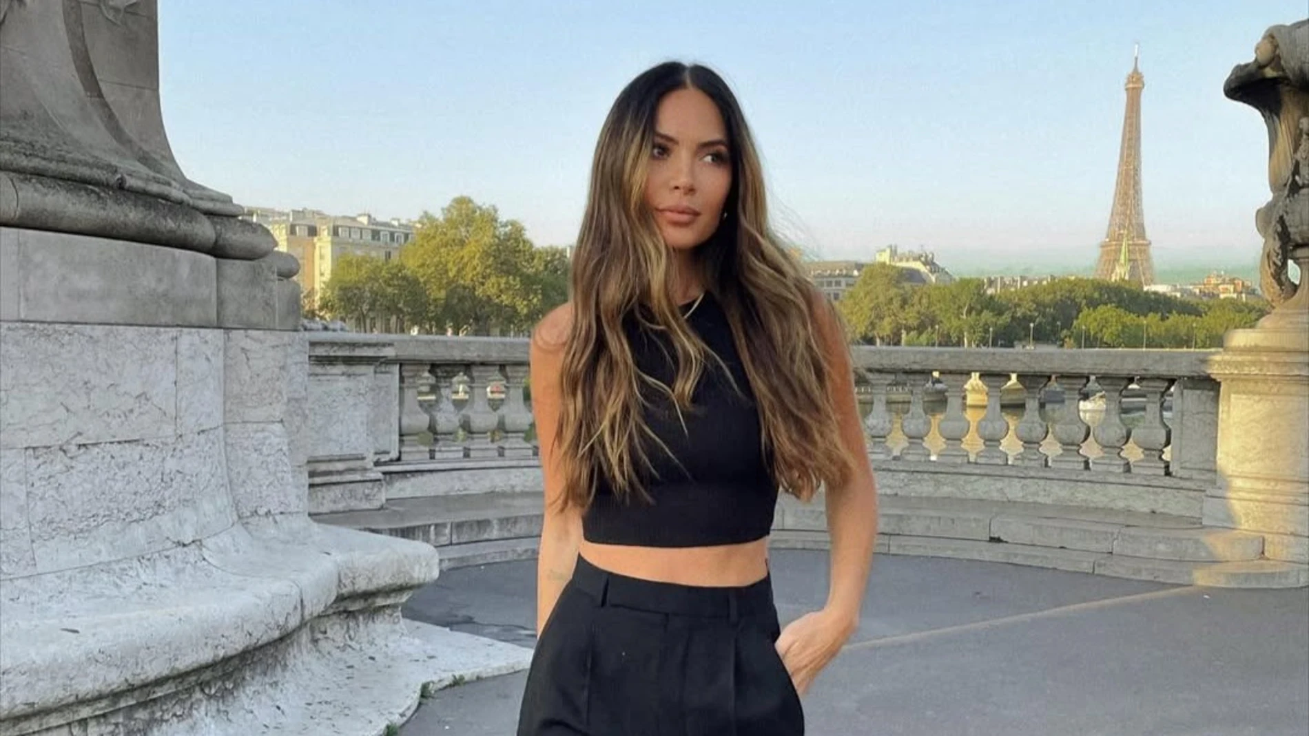 Marianna Hewitt posando al aire libre con melena ondulada y suelta, de espaldas a la Torre Eiffel.