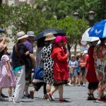 Turistas asiáticos se protegen del sol mientras hacen cola para entrar en el Real Alcázar de Sevilla