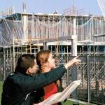 Dos jóvenes contemplan la construcción de un bloque de viviendas