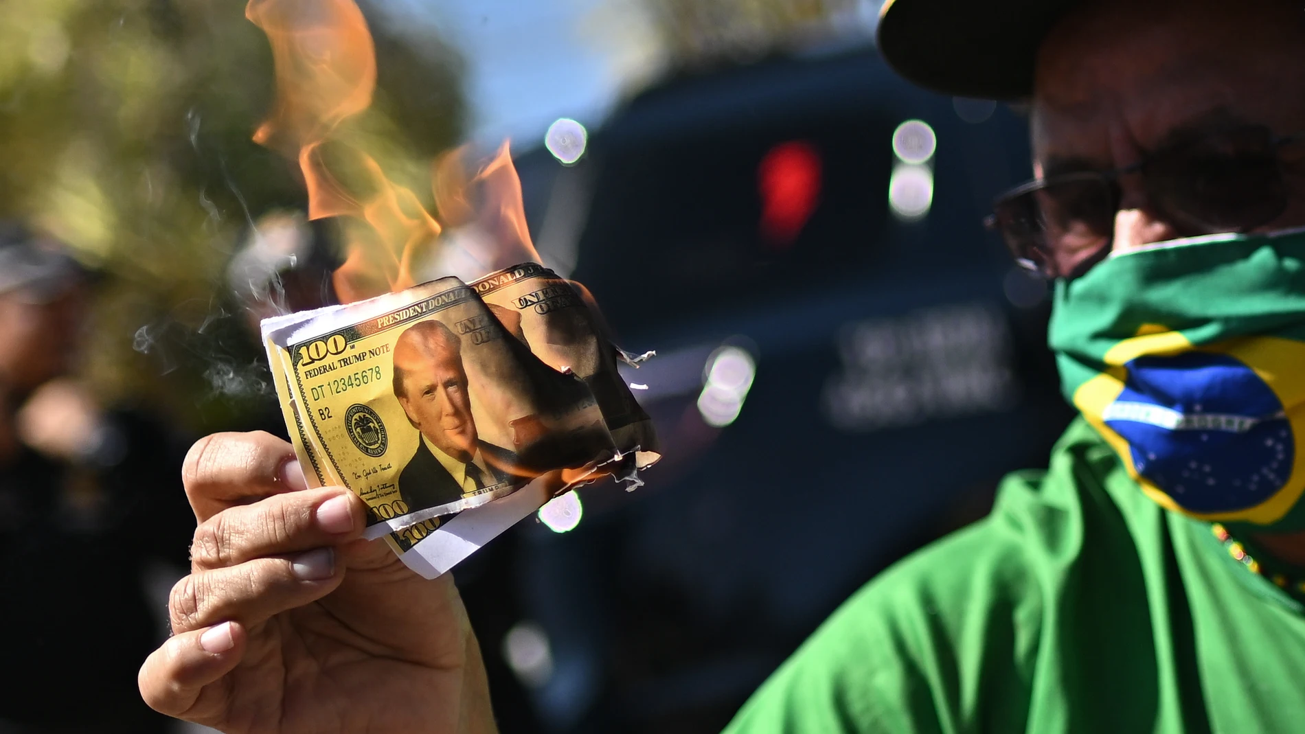 AME6864. BRASILIA (BRASIL), 01/08/2025.- Una persona quema un papel con la imagen de Donald Trump durante una protesta contra los aranceles estadunidenses ante Brasil este viernes, frente de la Embajada de Estados Unidos en Brasilia (Brasil). EFE/ Andre Borges