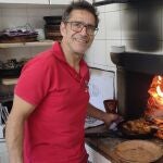 Marcos Benito, asador del Restaurante María Eugenia de Peñafiel, posa con un cuarto de lechazo junto al horno de leña