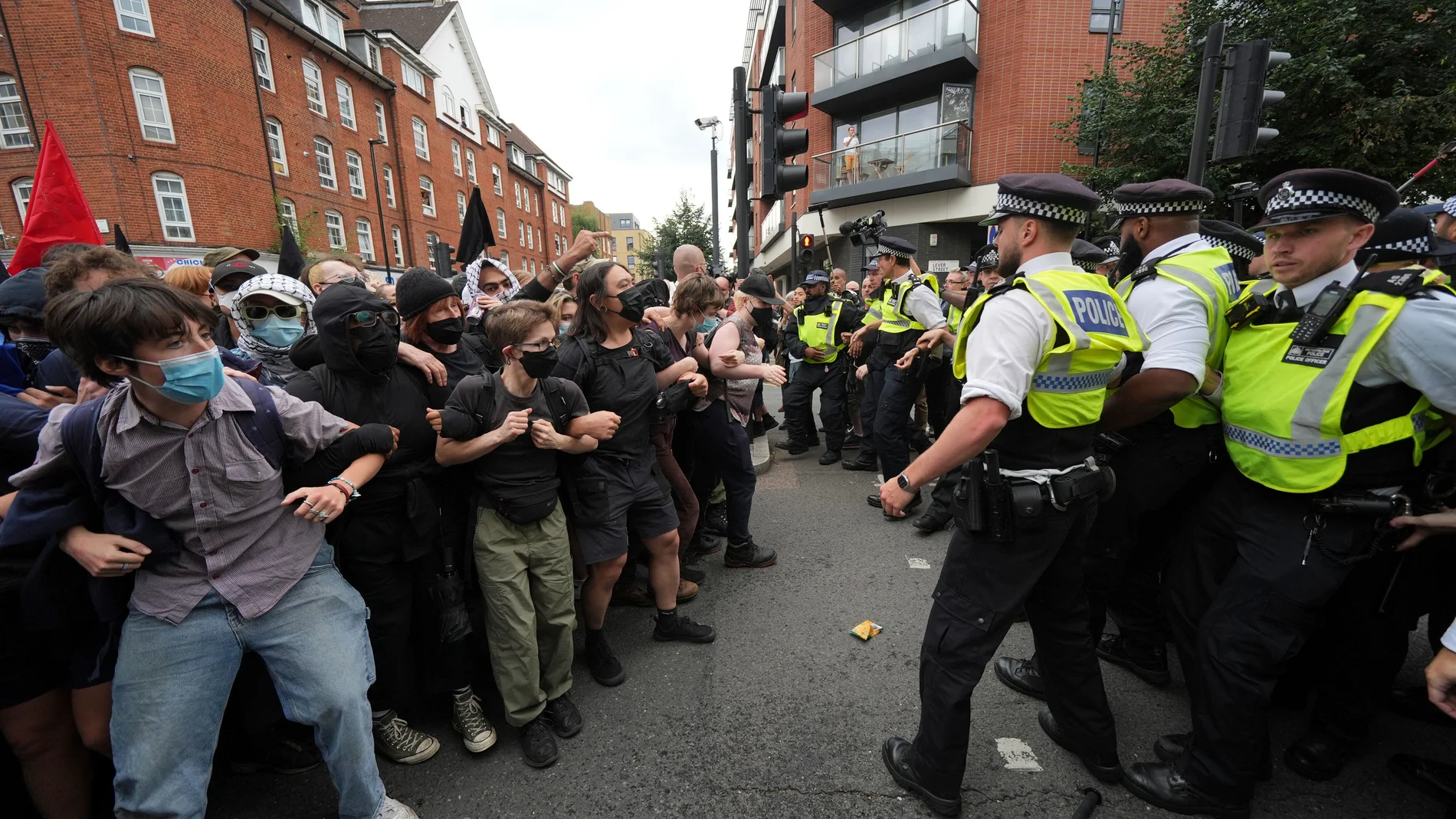 Police form a barrier in front of protesters outside the Thistle City Barbican Hotel in central London, which houses asylum seekers, Saturday Aug. 2, 2025. (PA via AP)