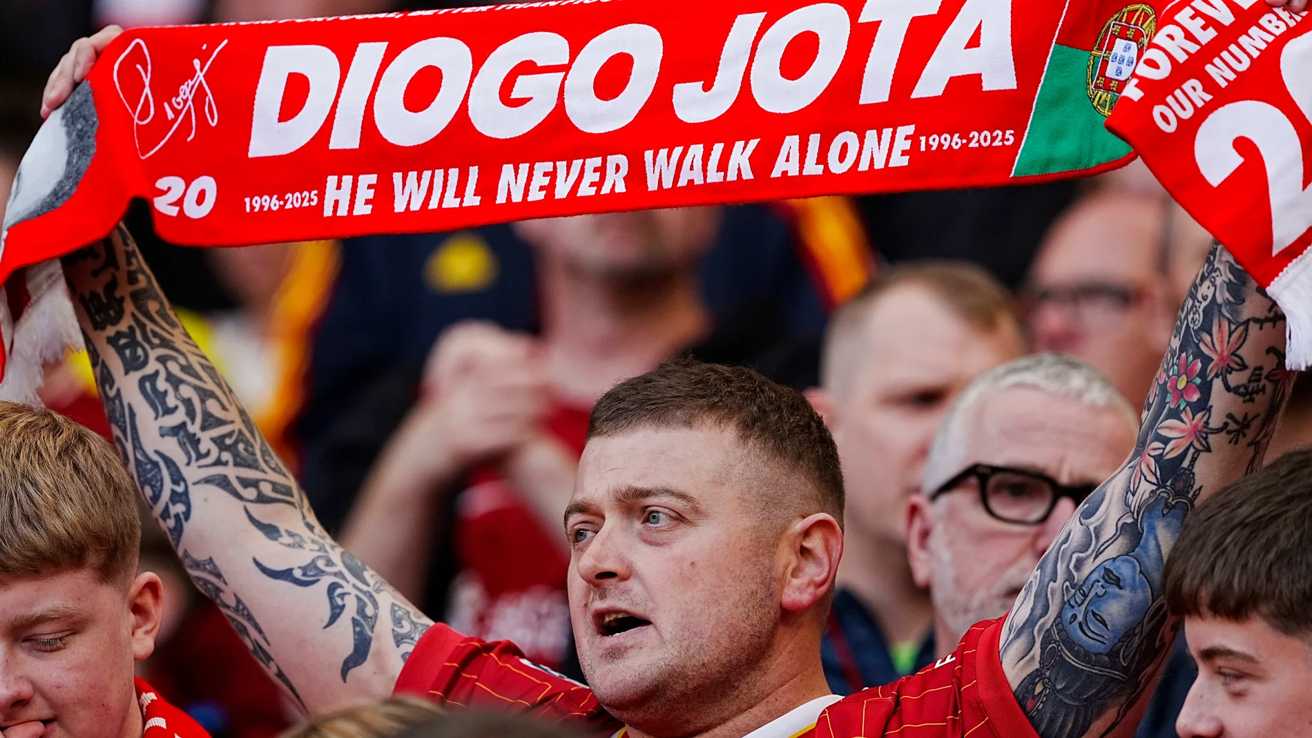 Liverpool fan holds up a scarf in trubute for Diogo Jota before the pre-season friendly soccer match between Liverpool and Athletic Bilbao, at Anfield, Liverpool, England, Monday Aug. 4, 2025. (Peter Byrne/PA via AP)
