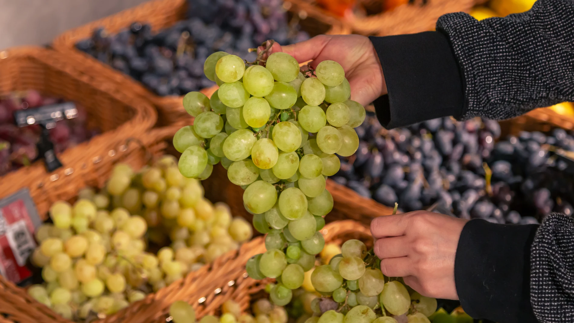Una mujer escoge uvas en un supermercado