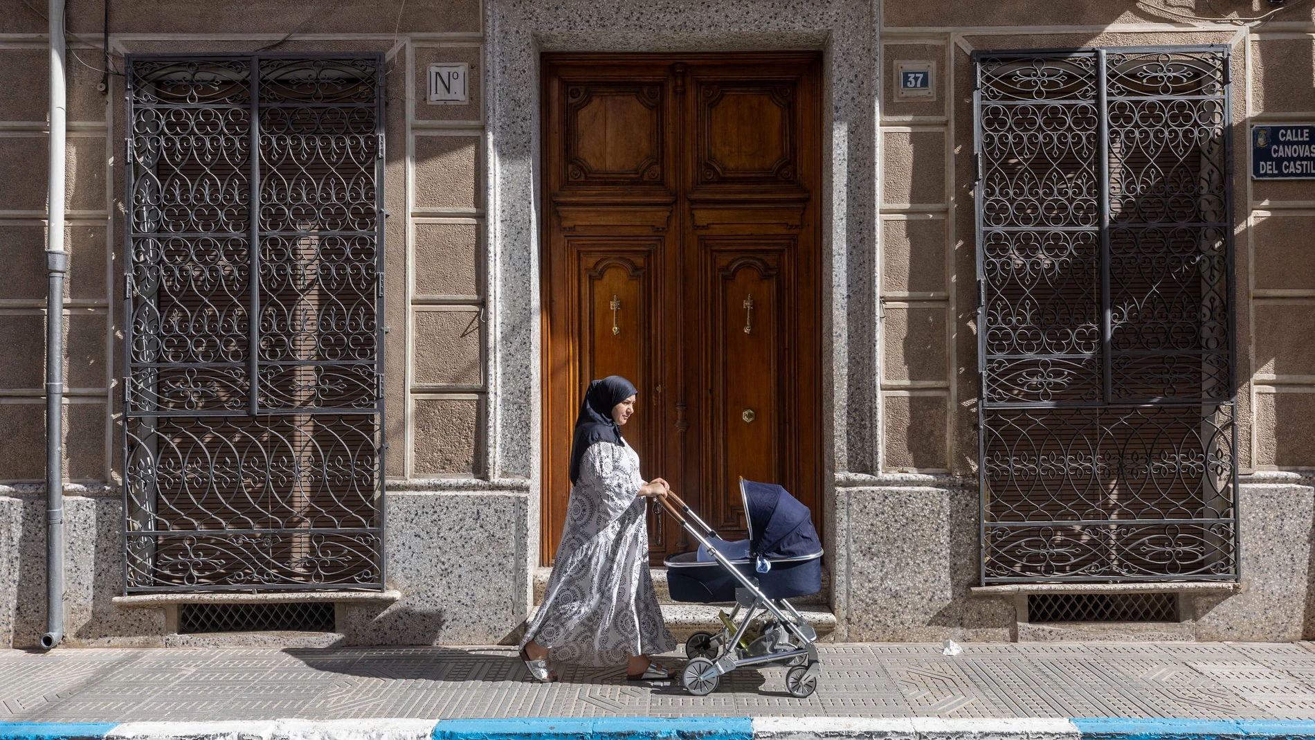 JUMILLA, (MURCIA), 07/08/2025.- Una mujer de origen marroquí camina con el carrito de su bebé, este jueves por una calle de Jumilla. La decisión del Ayuntamiento de Jumilla, un pueblo del sureste español gobernado por la derecha y donde residen miles de inmigrantes, de prohibir actos religiosos en espacios municipales donde se celebraban ceremonias islámicas como el fin del Ramadán, ha desatado indignación e incertidumbre entre la comunidad musulmana semanas después de los incidentes racistas...