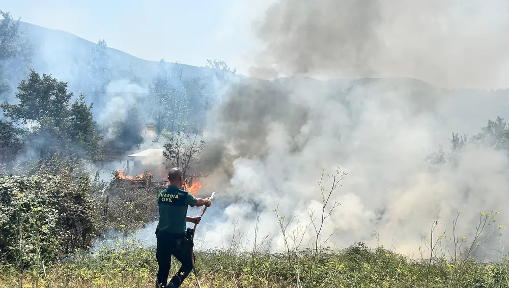 Un guardia civil intenta sofocar el fuego que afecta a uno de los municipios evacuados por el incendio originado en Yeres.