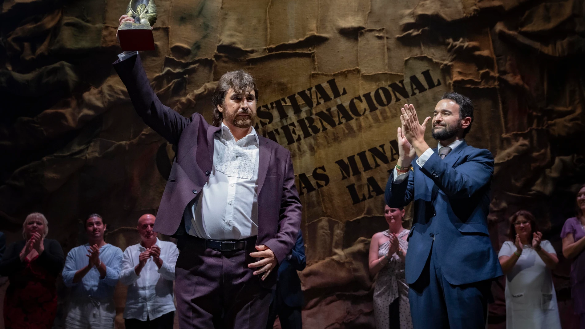 LA UNIÓN (MURCIA), 10/08/2025.- El cantaor manchego Gregorio Moya Lara (i) recibe el primer premio, la Lámpara Minera, de manos del alcalde de La Unión, Joaquín Zapata (d), en la final de la 64 edición del Festival Internacional del Cante de las Minas de La Unión este sábado en el Antiguo Mercado Público, también conocido como la Catedral del Cante . EFE/Marcial Guillén