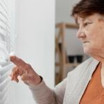 Mujer mayor regula las persianas para evitar la entrada de calor en casa