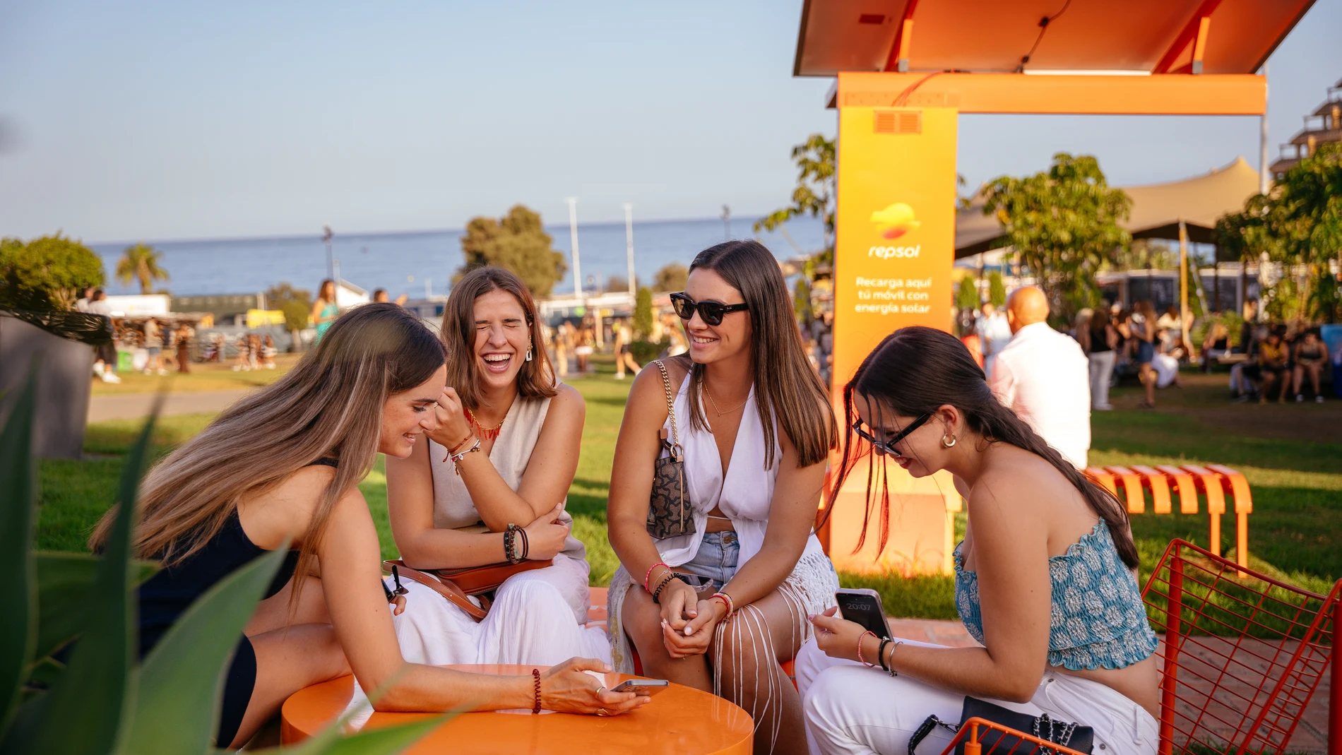 Grupo de amigas descansando en un espacio Repsol al aire libre en Marenostrum Fuengirola con el mar Mediterráneo de fondo